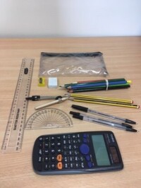 Example of exam equipment including a clear plastic pencil case, 3 black biros, 2 HB pencils, coloured pencils, ruler, protractor, compass, rubber, pencil sharpener and calculator without a lid.